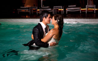 Wedding couple kissing after jumping in the pool with their clothes on